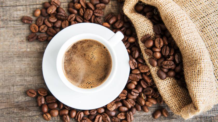 A cup of specialty coffee with coffee beans around it, representing Roasters Co.’s premium Latin American blends for home brewing.