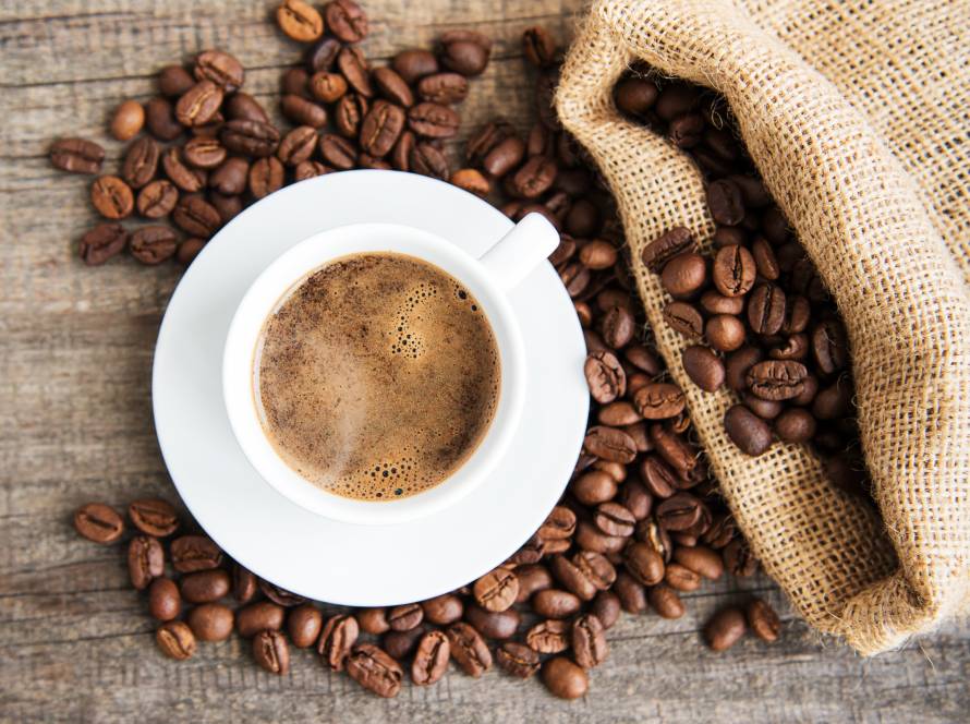 A cup of specialty coffee with coffee beans around it, representing Roasters Co.’s premium Latin American blends for home brewing.